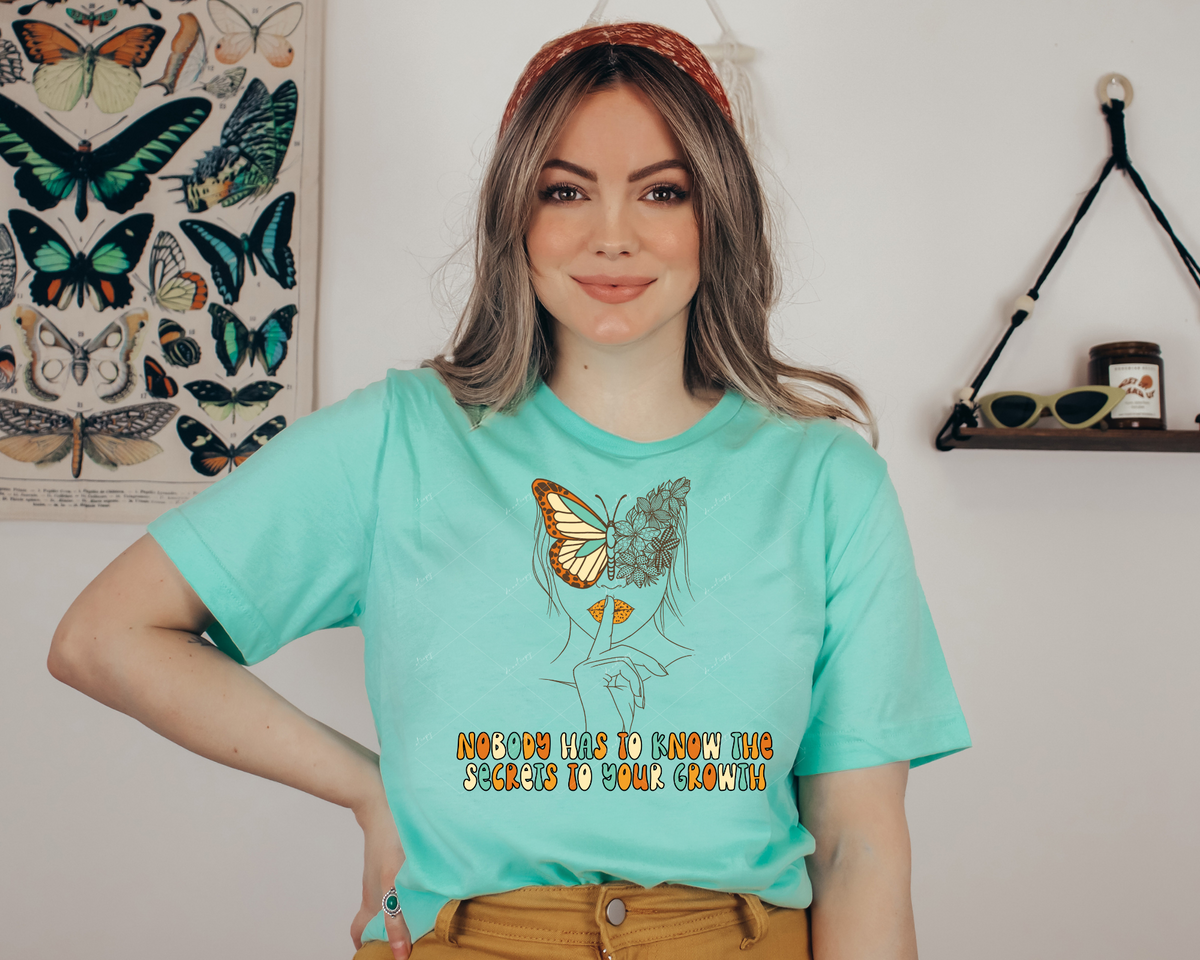 Nobody has to know the secrets to your growth (outline of woman face with butterfly, bubble lettering yellows, cream, and light turquoise colors) 1762 DTF TRANSFER